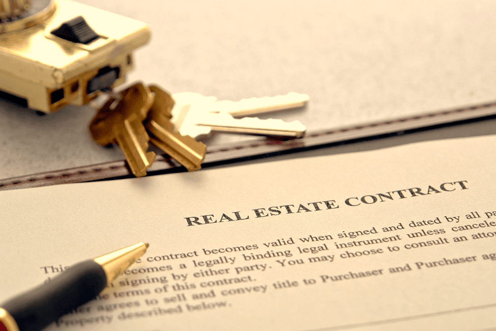 Close-up view of a real estate contract with a pen and keys placed on top of it.